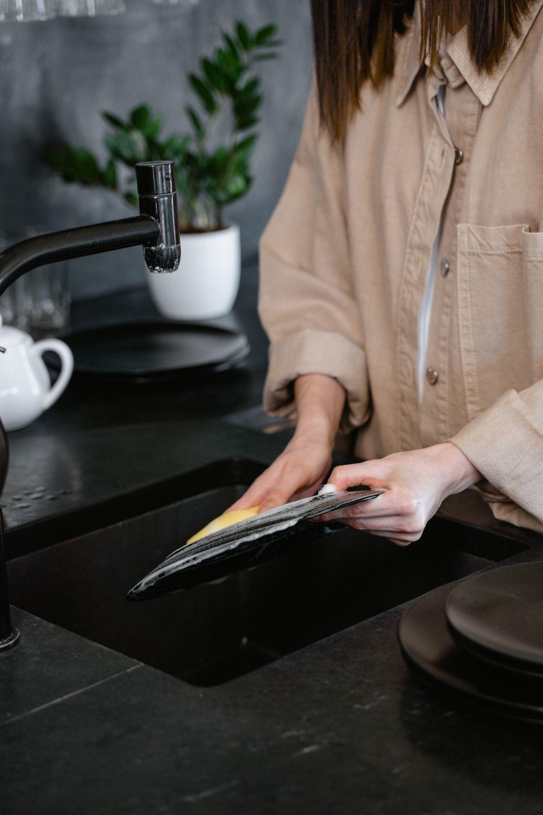 Một bạn đang rửa bát trong bếp chung